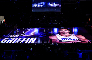 A player card introducing a Tulsa basketball player lights up the court with projection mapping.