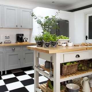 kitchen area with white wall and tiles flooring with wooden kitchen worktop and cabinet