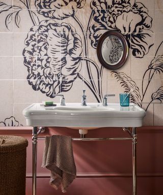 An example of bathroom paint ideas showing a traditional white sink in front of pink wall tiles with a floral wall mural