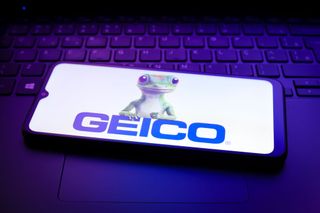 GEICO logo with the GEICO lizard on smartphone placed on top of a keyboard