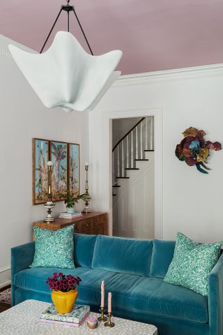 A living room with pink ceiling, and turquoise sofa