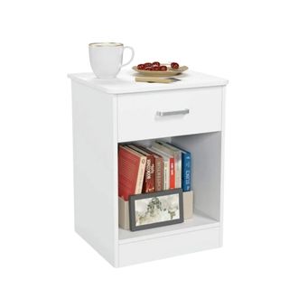A white nightstand with books underneath it and a coffee cup on top of it