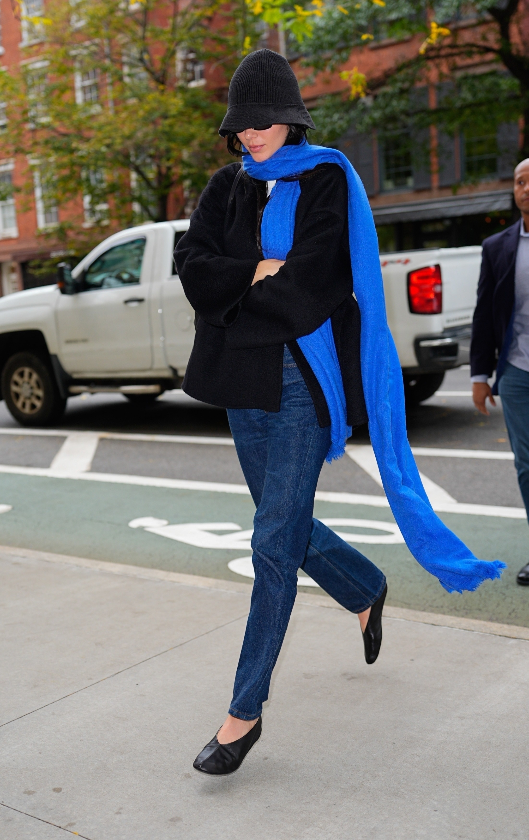 Kendall Jenner wearing a black jacket, blue jeans, and a cobalt blue scarf