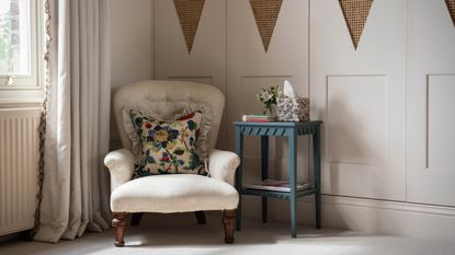 bedroom with fitted wardrobes in taupe, plain upholstered armchair with floral couch pillow, blue side table, curtains with fringing, Georgie Wykeham Designs