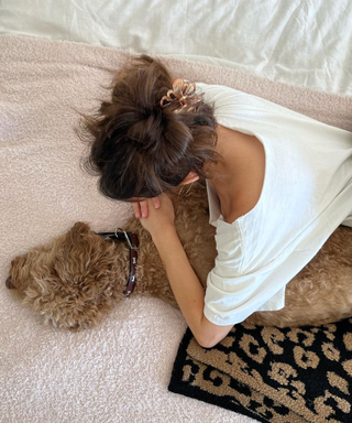 Madison Beer and her dog in bed with a black and brown leopard print blanket