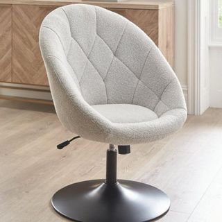 A white boucle bucket chair with a black bowl leg