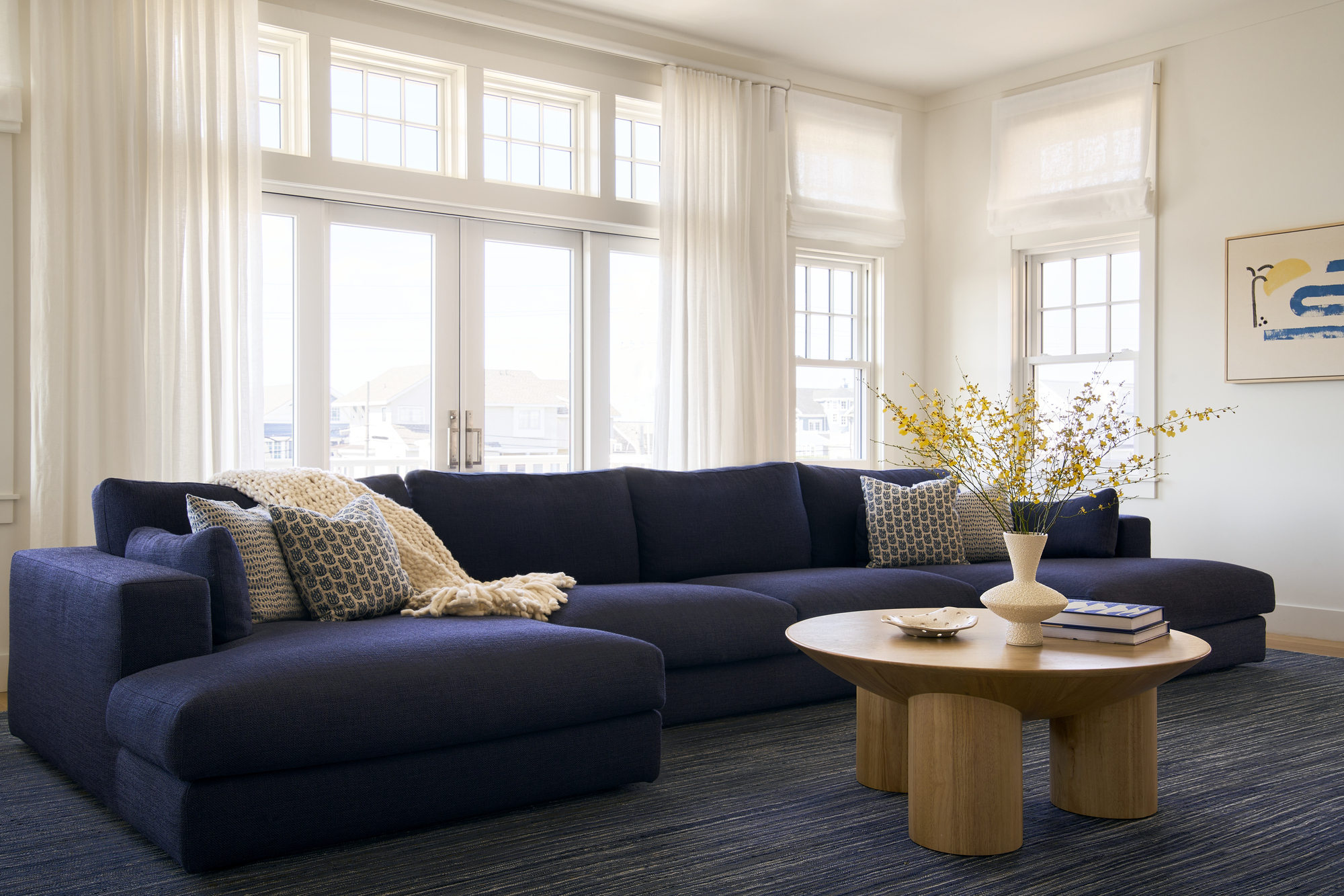 neutral living room with blue sofa, blue rug, round timber coffee table