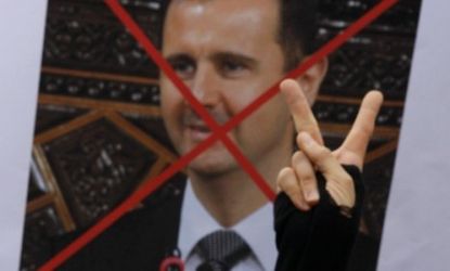 Syrian protesters hold a sign featuring President Bashar al-Assad: