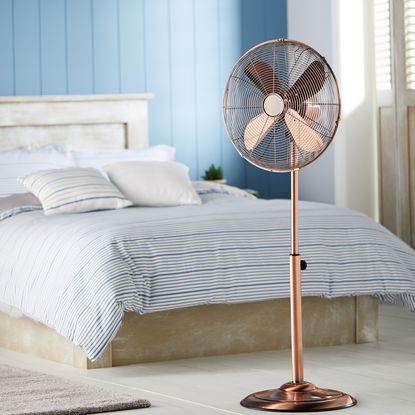 bedroom with oscillating stand fan and sky blue wall