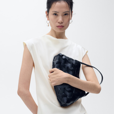 Mango model wearing white satin draped t-shirt and black woven shoulder bag.