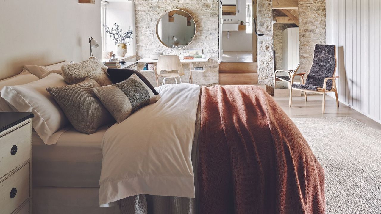  Bedroom with wooden floor, rattan rug, double bed below vaulted ceiling.