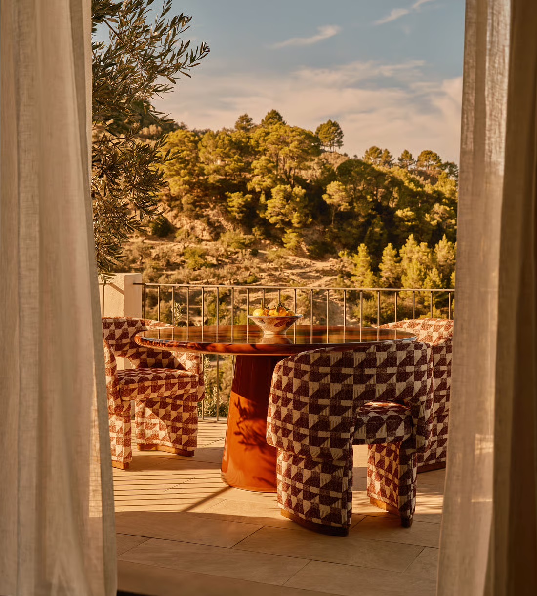 Curved outdoor dining chairs around a circular table on a terrace