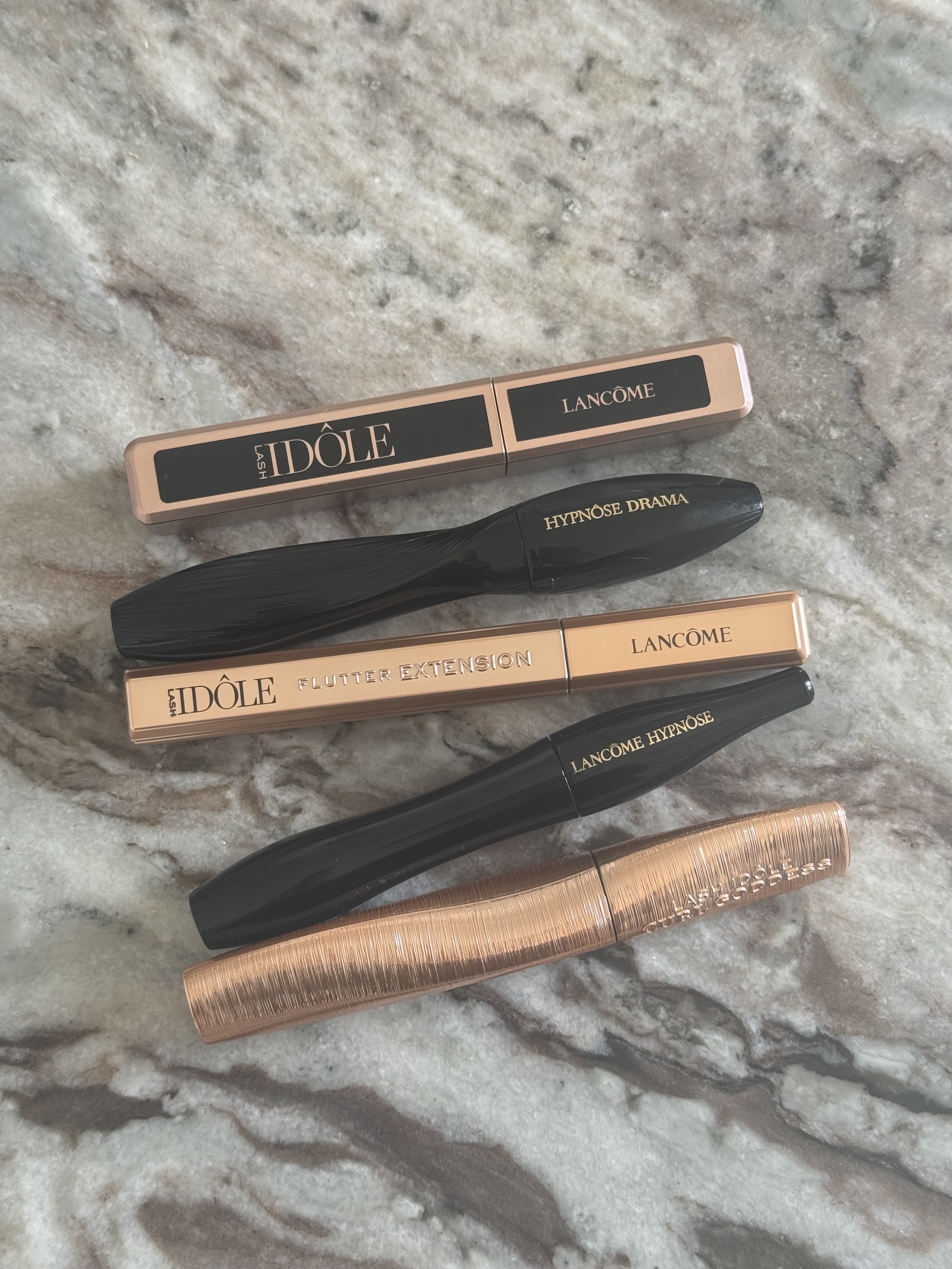 A selection of Lancome mascara tubes on a marble table