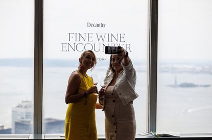 Two women taking a selfie in front of a 'Decanter Fine Wine Encounter' sign