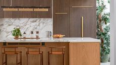 timber kitchen with marble counters, a pot plant, jars, kettle, and fruit bowl