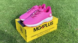 The striking pink G/Fore MG4+ Womens Golf Shoe resting on its yellow box on the fairway
