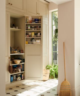 a light yellow themed walk-in pantry with a geometric tiled floor