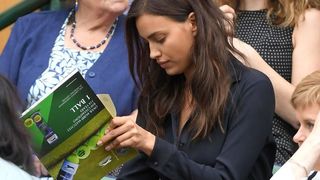 Upset Irina Shayk looking at upside down magazine in the crowd at Wimbledon
