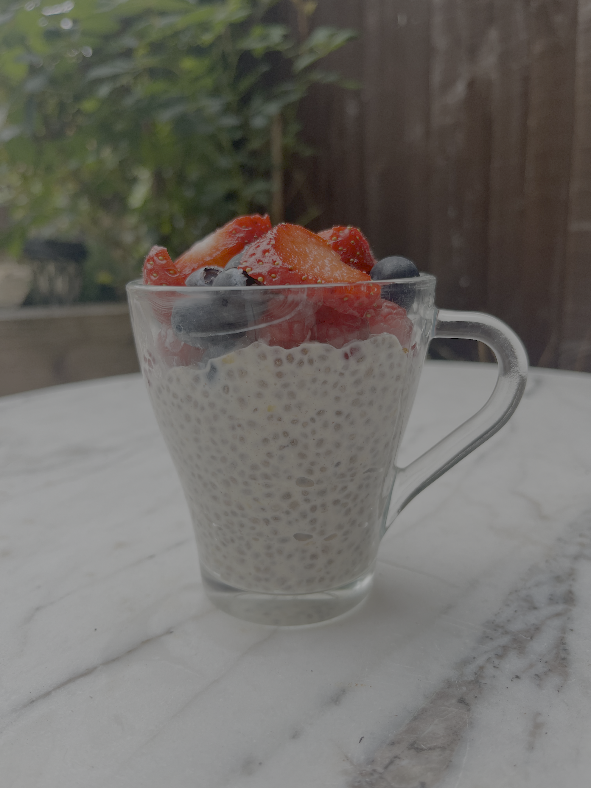 A chia seed pudding with strawberries and blueberries on a white table