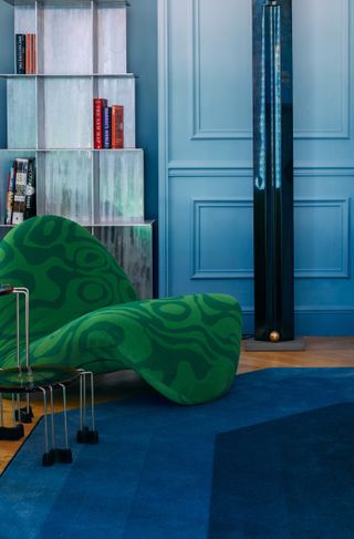 A living room with emerald green chair and deep blue carpet
