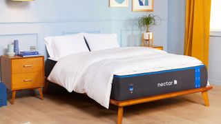 The Nectar Memory Foam Mattress shown with a white comforter in a bedroom with yellow drapes