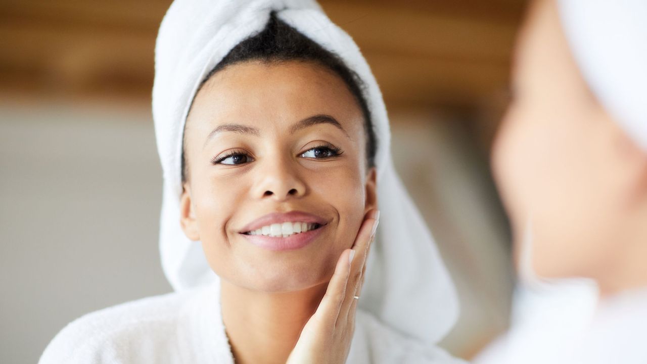 woman examining her clear radiant skin in a mirror