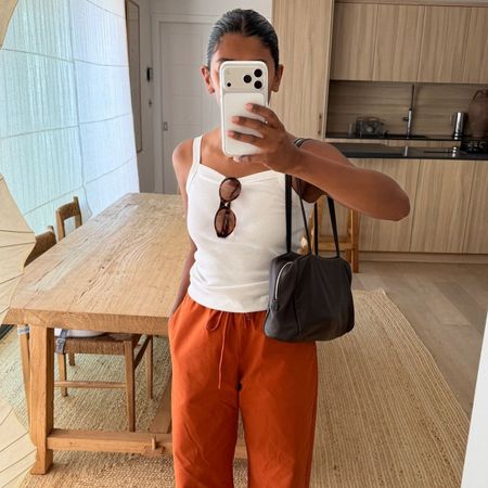 @monikh taking a mirror selfie wearing orange trousers and white vest