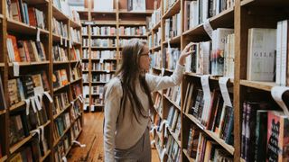 Person browsing books on a book shelf