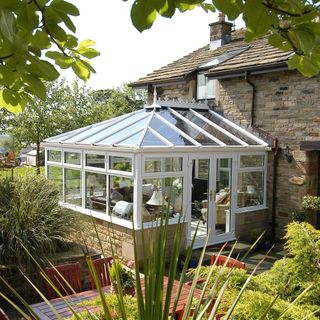 white conservatory with patio table and trees