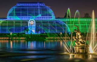 Christmas lights display at Royal Botanic Gardens, Kew, London, England, featuring the famous Palm House and Pond.