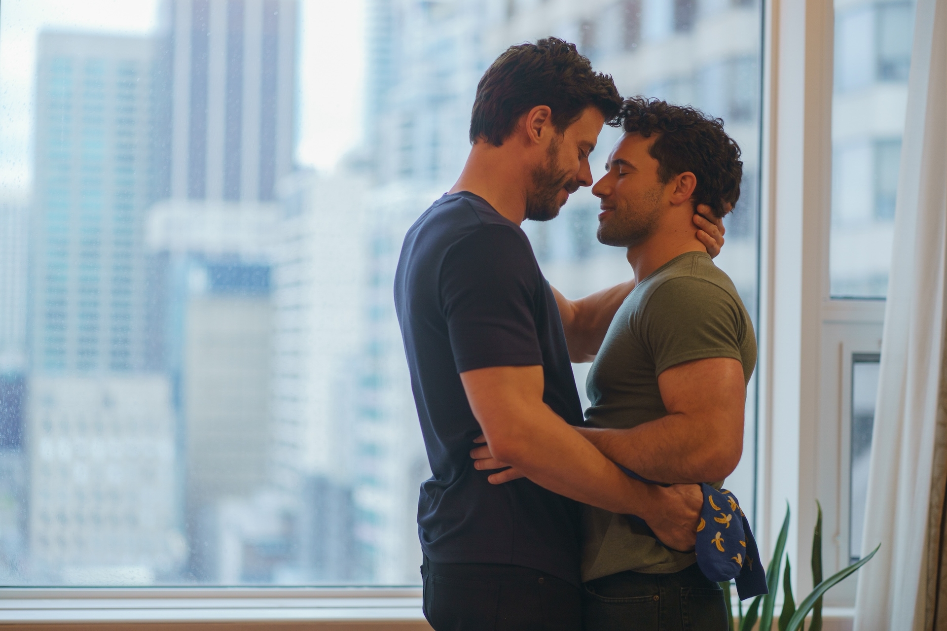 Fran&amp;ccedil;ois Arnaud as Scott Hunter and Robbie G.K. as Kip Grady embracing each other in a high rise apartment in Episode 103 of Heated Rivalry