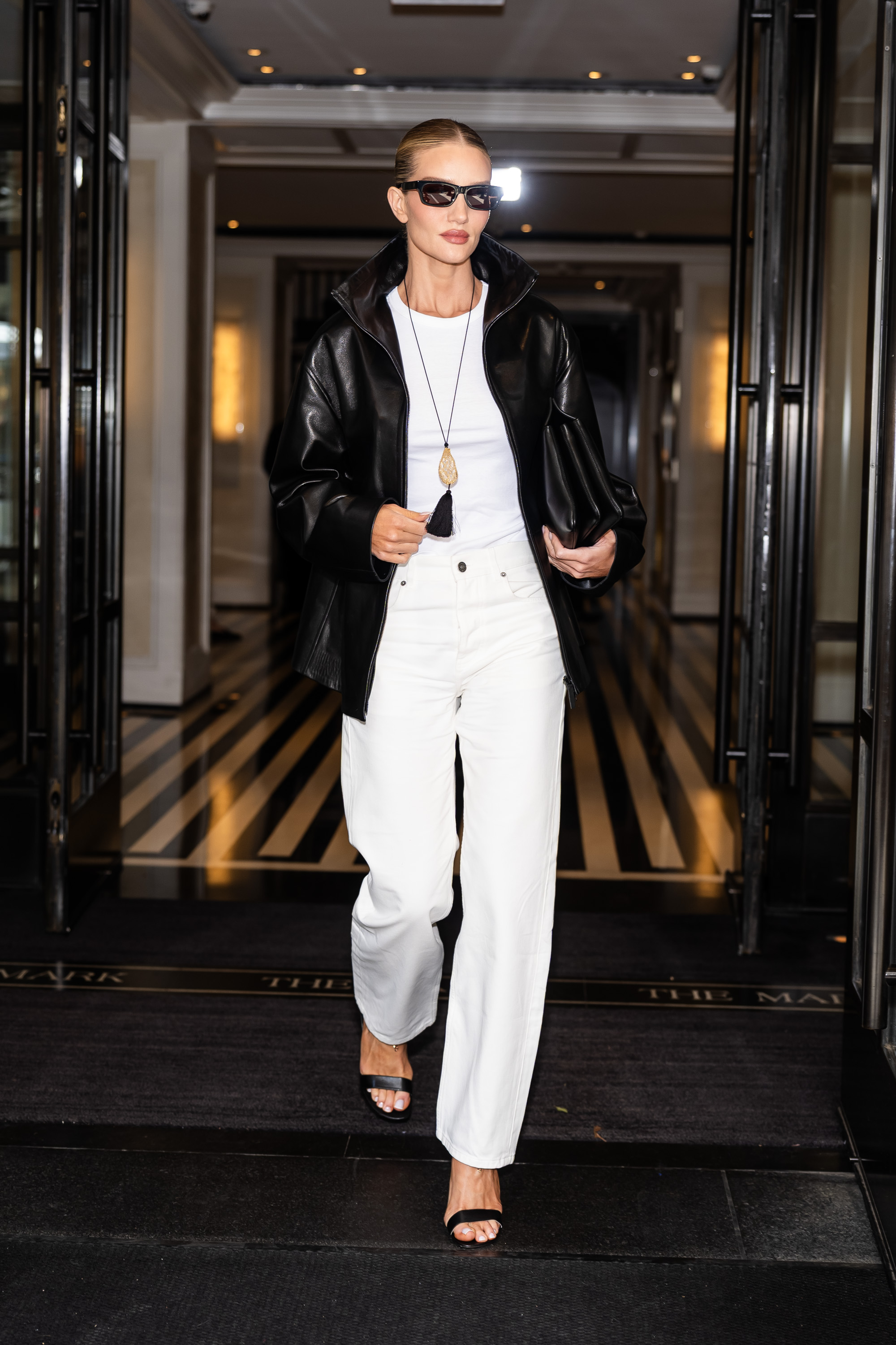 Rosie Huntington Whiteley wears white jeans with black sandals.