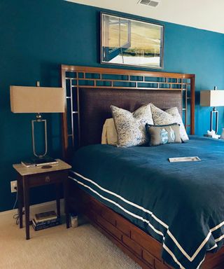 A teal blue bedroom with a brown bed with teal bedding and a white lamp next to it