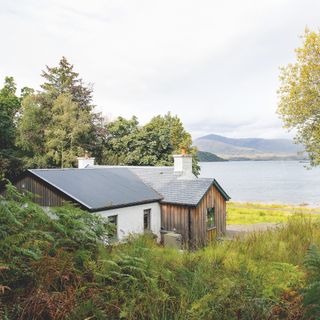 exterior of cottage on Isle of Mull with mix of woodclad exterior and white render with view over loch