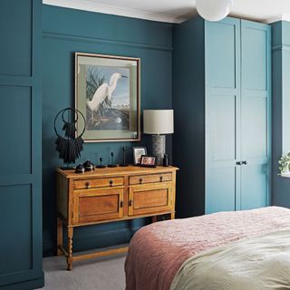 blue bedroom with wooden furniture and pink bedspread