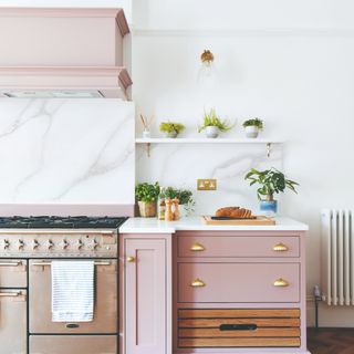 Pale pink kitchen cupboards in white marble kitchen