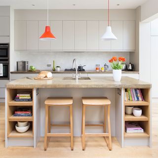 island with wooden stools and orange and white pendant lights