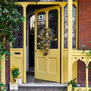 yellow front door with stained glass windows and wreath