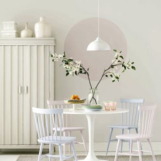 White dining room with round table, pastel chairs and paint affect on wall