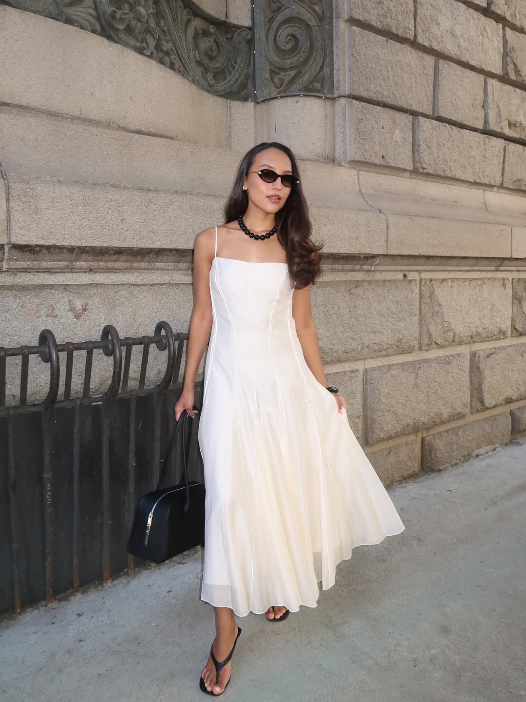 Ingrid in a white dress and black heeled flip-flops