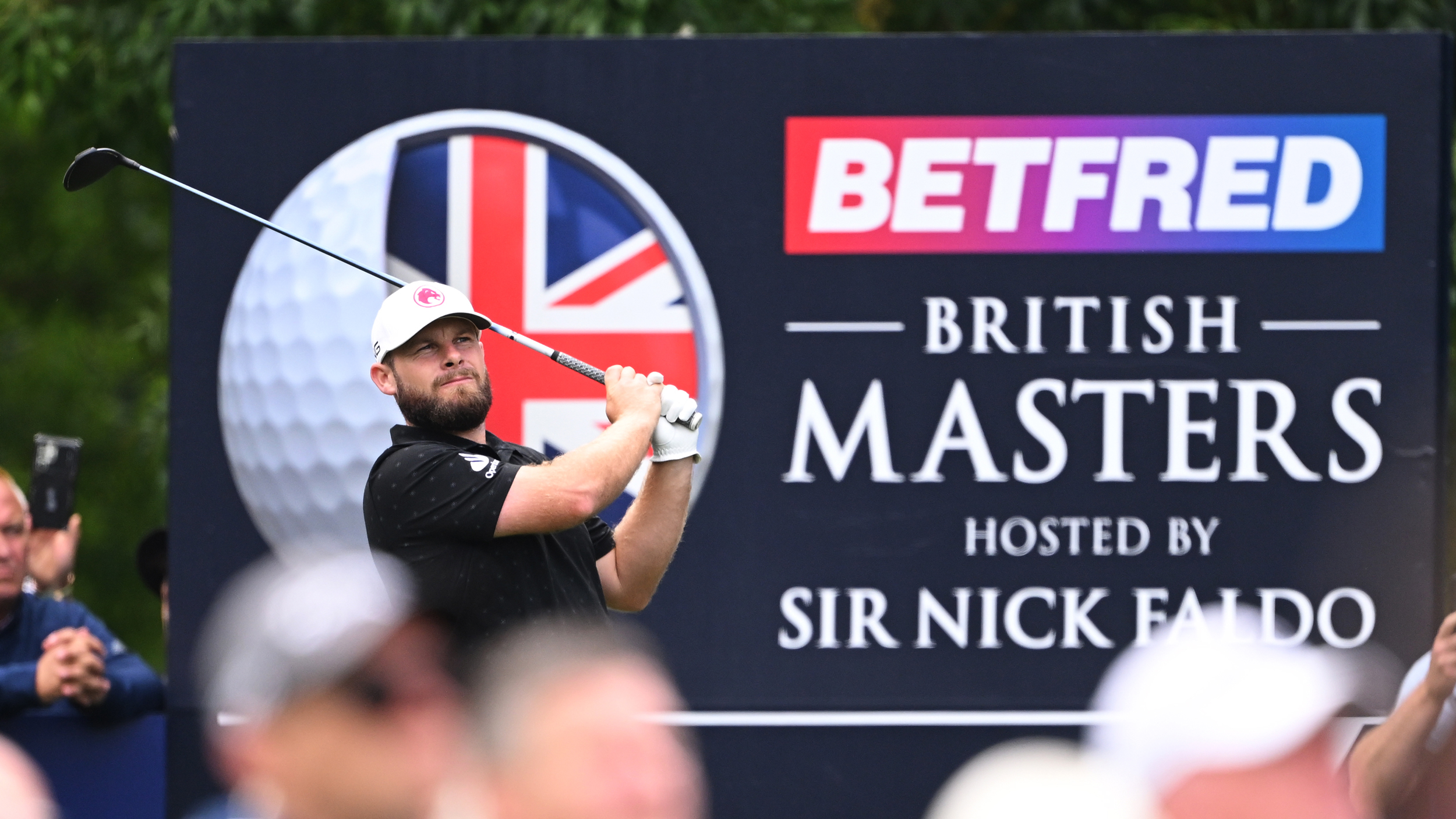 Tyrrell Hatton holds his finish on a drive in front of a Betfred British Masters signage
