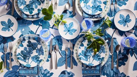 Blue fig pattern-drenched tablescape featuring linens, plates, and cutlery from Peter Dunham's vibrant new tableware collaboration with Hudson Grace