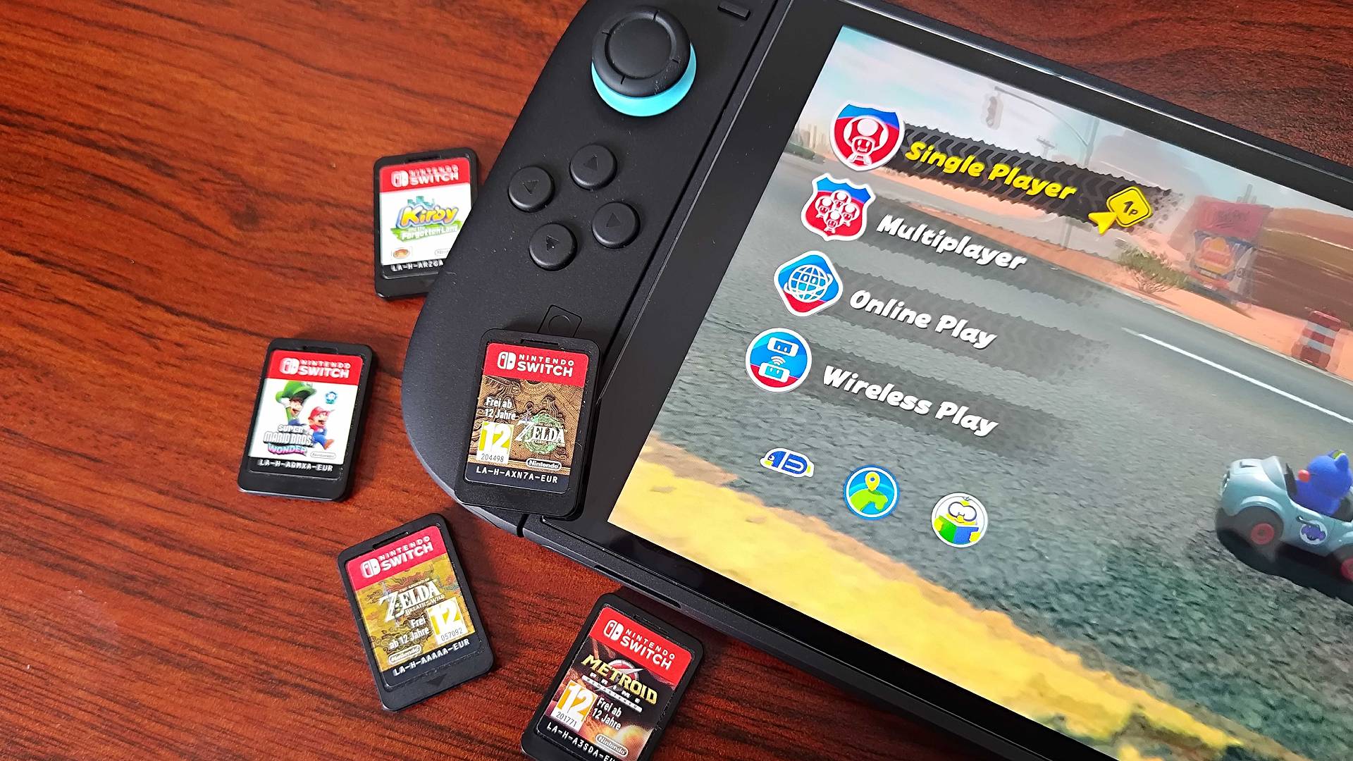 Nintendo Switch 2 console on woodgrain desk surrounded by Switch cartridges.