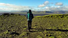 Best walking trousers a man walks along the top of a steep, grass covered hill