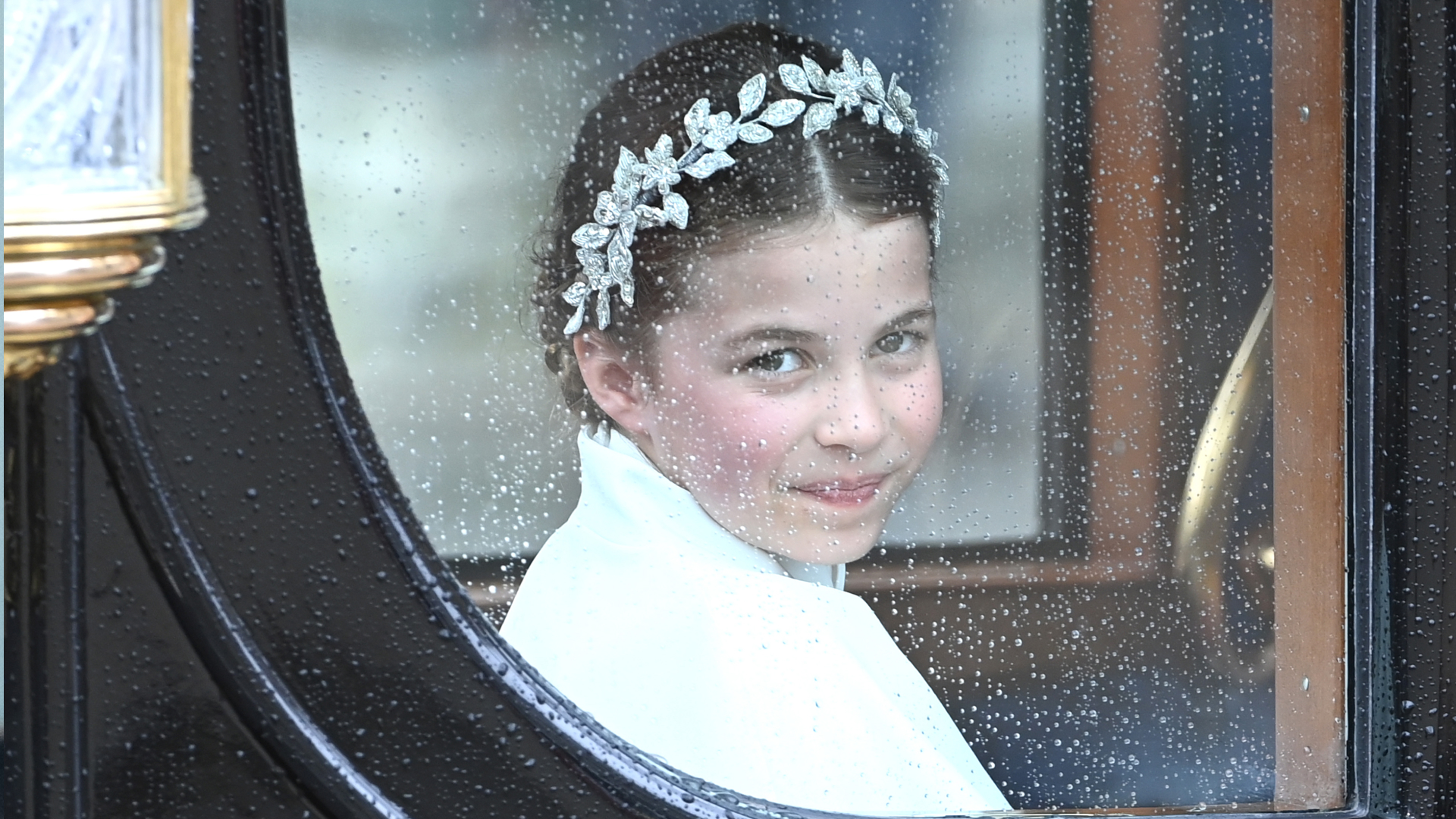 Princess Charlotte wearing a diamond leaf crown riding in a carriage at King Charles's coronation