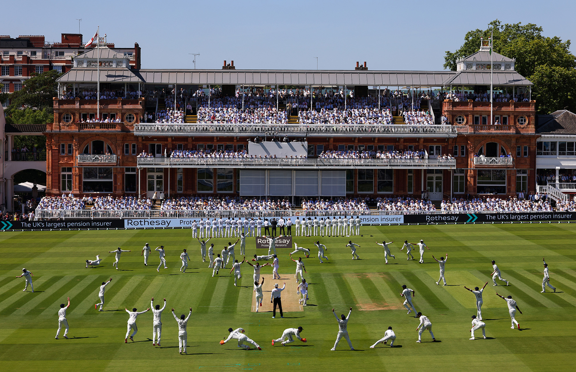 Lords Pavillion with cricketers on the pitch