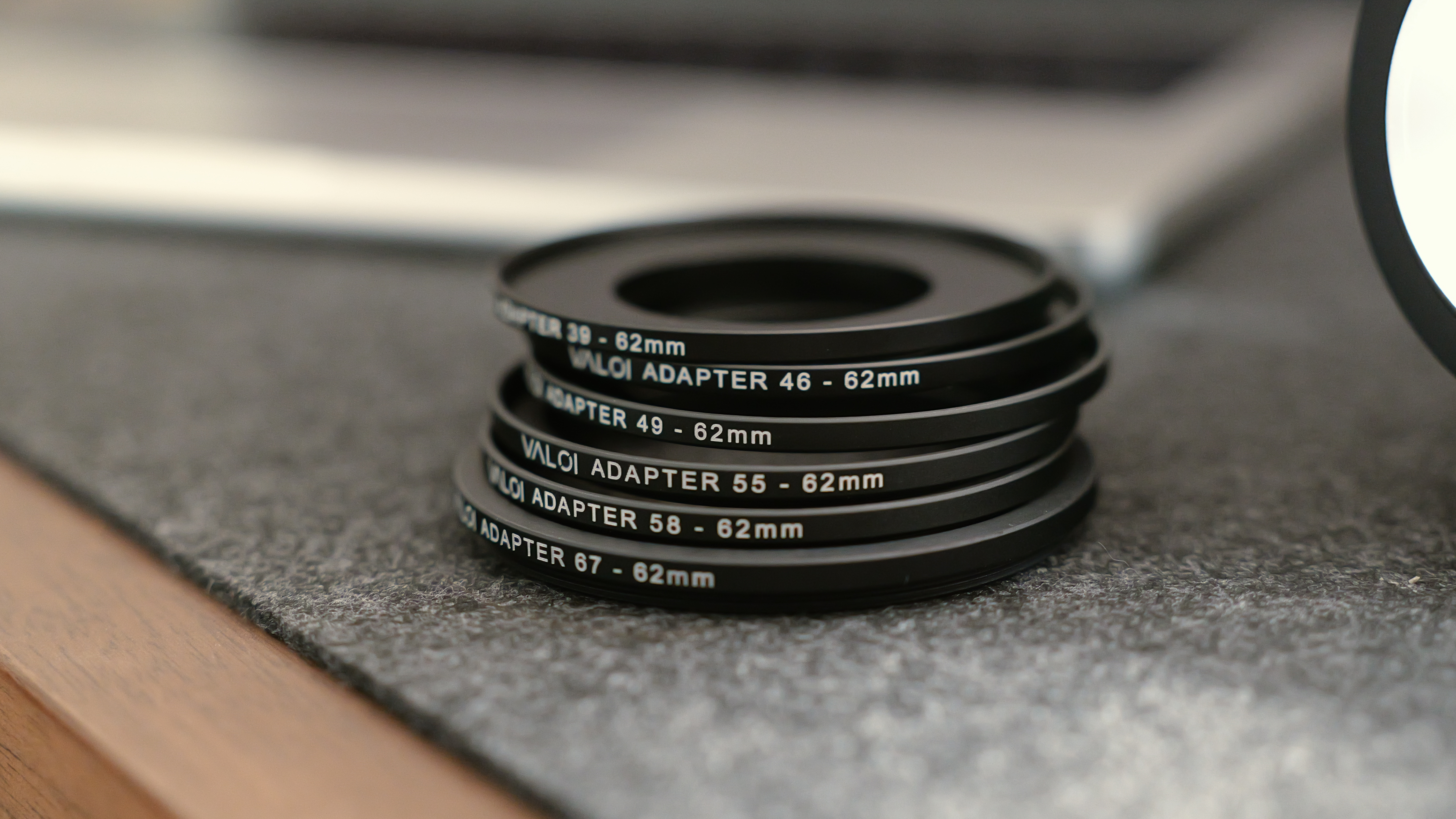 A close-up of stacked Valoi adapter rings for fitting different lens thread sizes to a 62mm mount.