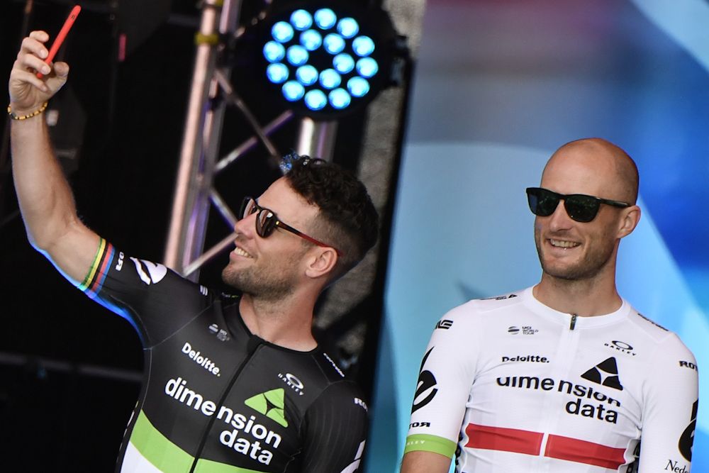 Mark Cavendish (L) takes a selfie picture next to Great Britain's Stephen Cummings as they stand on stage during the team presentation