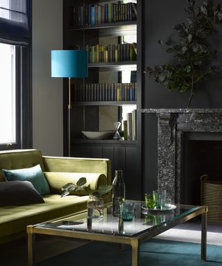 black painted living room with green sofa, mirrored alcove shelving and turquoise shaded floorlamp