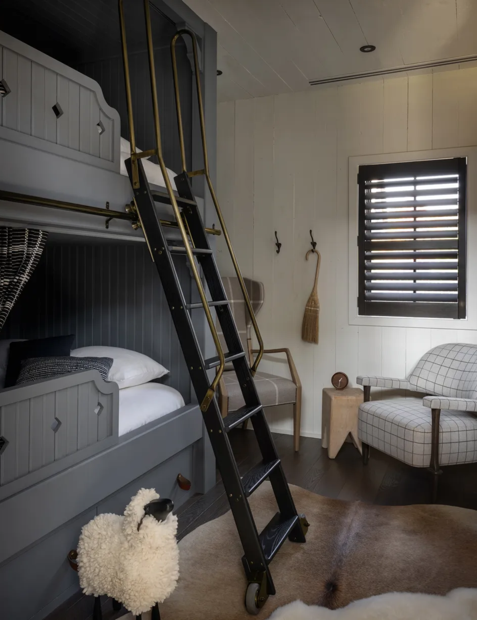 A bunk bed room with grey beds and black steps with a brass handle